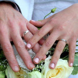 Mains avec alliances sur bouquet de mariage