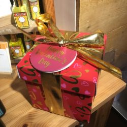 Jolie boîte rouge à petits coeurs roses et dorés, entourée d'un ruban doré