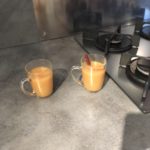 Deux tasses transparentes contenant un jus de pommes trouble et un bâton de cannelle