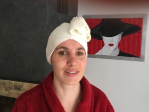 Flo en peignoir rouge avec serviette beige sur la tête