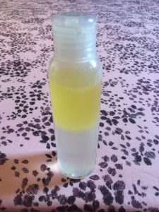 Bouteille transparente dont la partie basse est remplie d'un liquide transparent, la partie supérieure d'une huile jaune pâle.