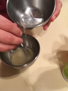 De l'alcool est versé d'un bol en inox dans un autre, contenant du gel
